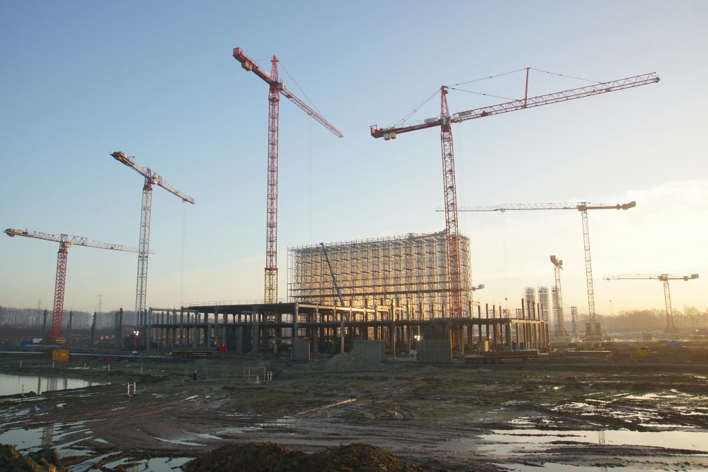 Business Structuring Wide view of a construction site with cranes and building framework at sunset. Industrial landscape.