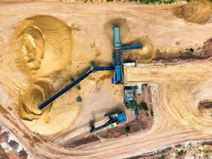 Drone shot of a sand quarry with conveyor belts and machinery in operation.